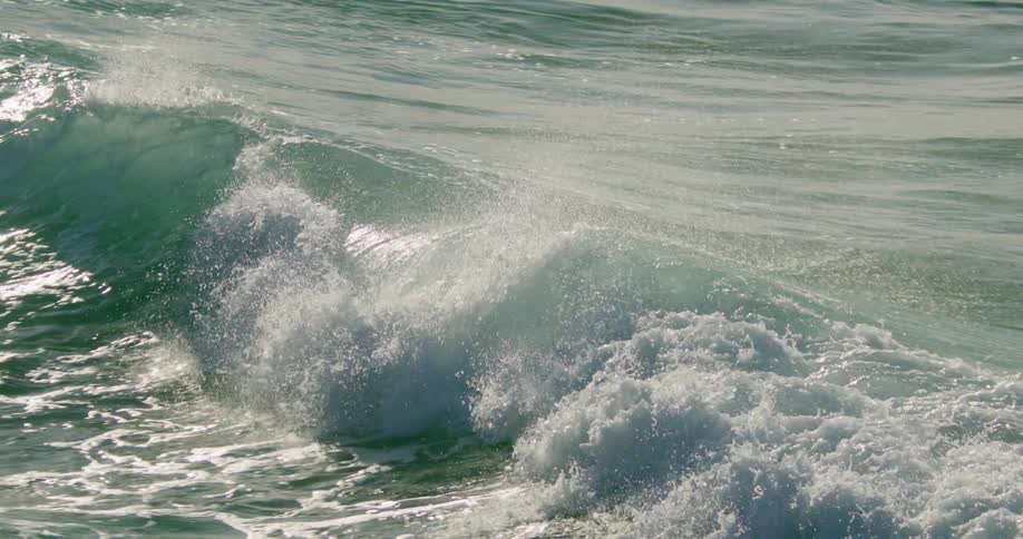 Large waves rolling along the ocean sending mist into the air