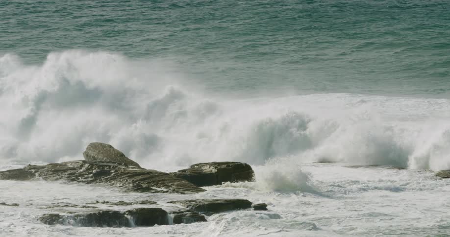 Ocean waves washing over a rock formation on a sunny day