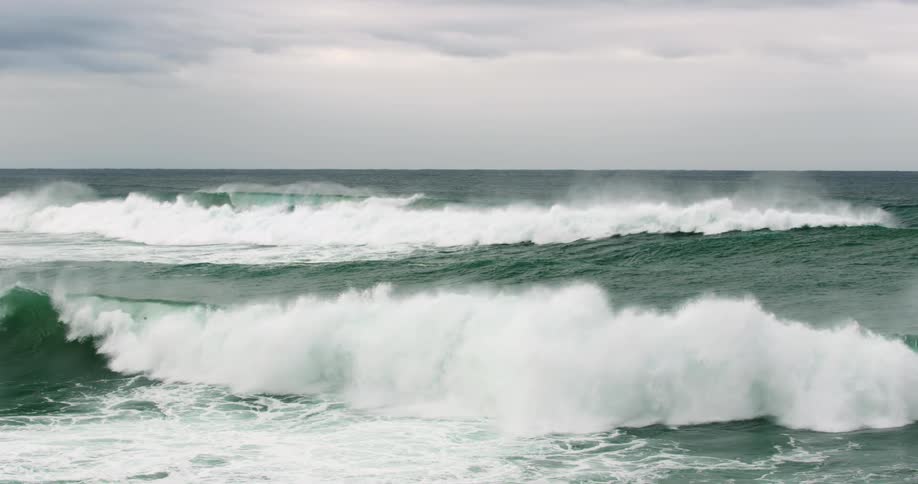 The ocean with water and waves with a bird flying above and the sky in the background
