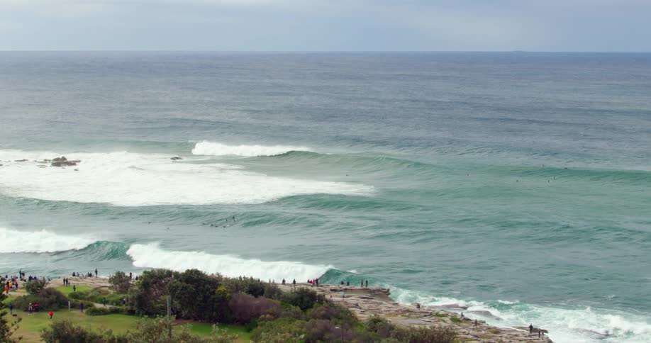 Bluegreen waves wash into a coast where people relax and watch