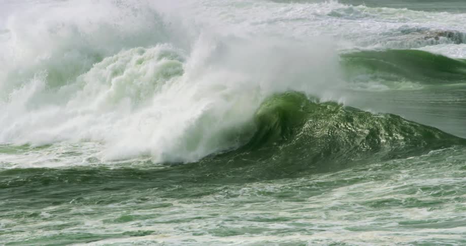 An ocean wave curls and breaks splashing and foaming