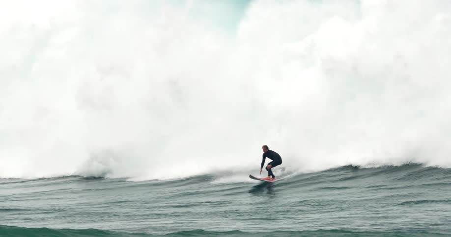 A surfer stands on his surfboard as he rides a wave but is soon swept of his feet by the water