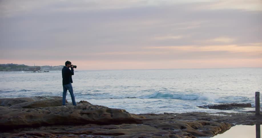 A man is taking photos at sunset on the beach