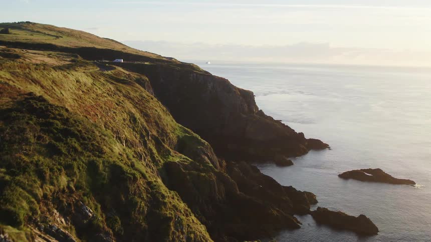 A road winds along the cliffs above the shore