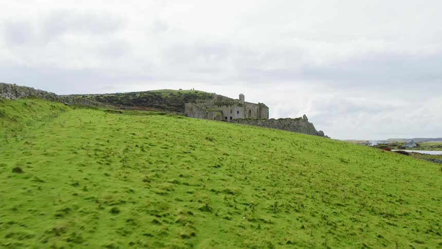 A large stone building on top of a grassy hill