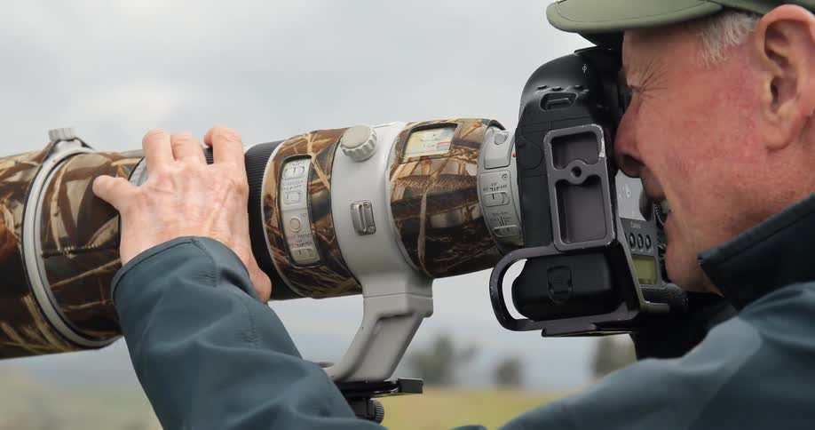 A man is using a camera with a very large lens