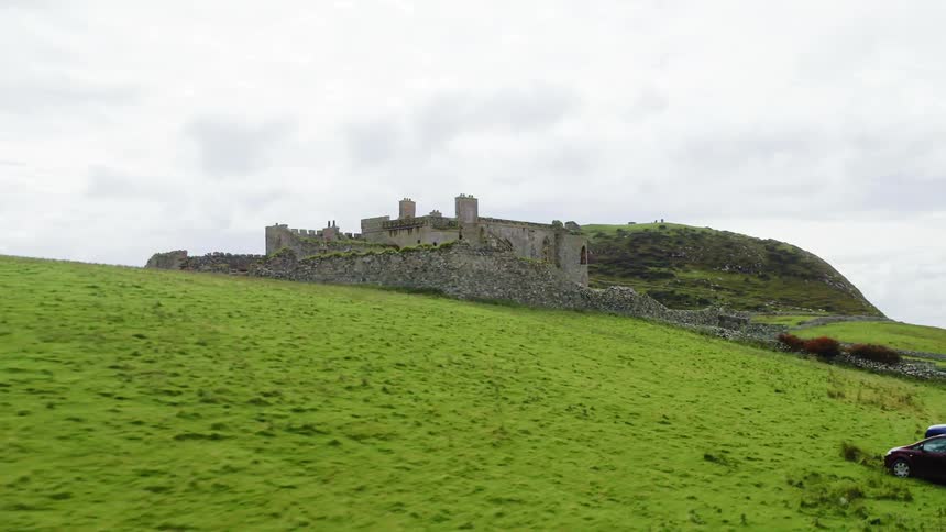 Cars are parked outside the monument of an old castle