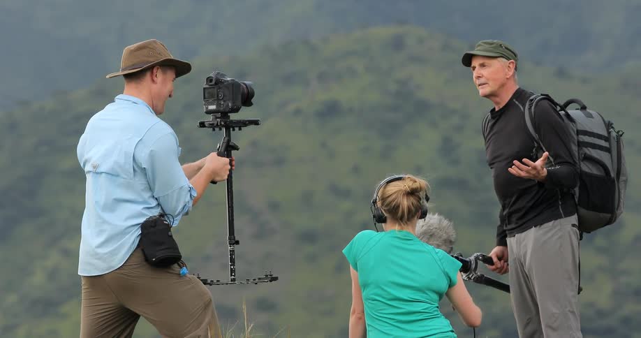 A man is talking with two people holding a camera and microphone
