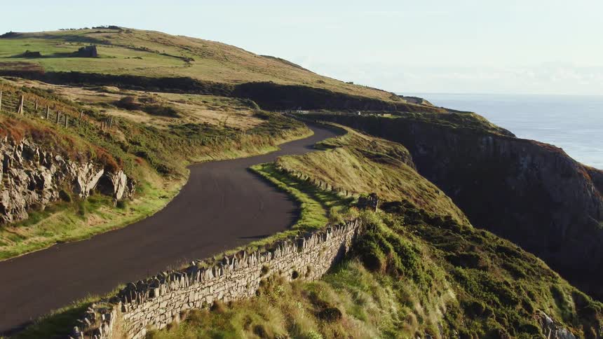Aerial view of two cyclists with helmets and jerseys cycling up a mountain road