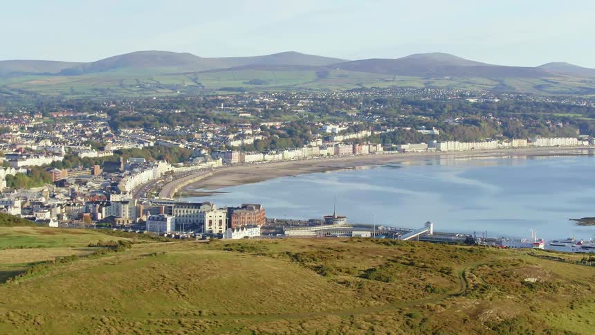 The city sits by the water over the green hill