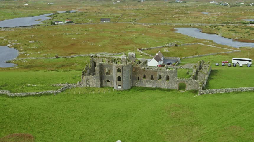 Castle ruins lie on a grassy hill near small bodies of water