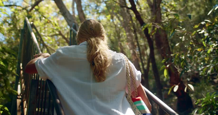Blonde girl with a ponytail and a white shirt climbs stairs outdoors