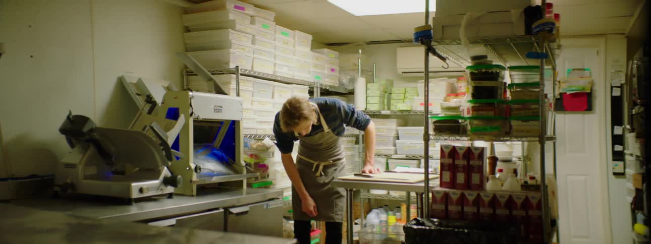 A man selects onions in the store room of a kitchen