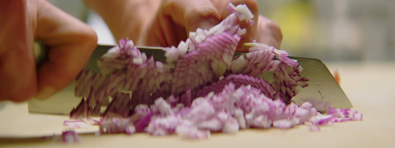 Man in an apron chopping onions in a kitchen