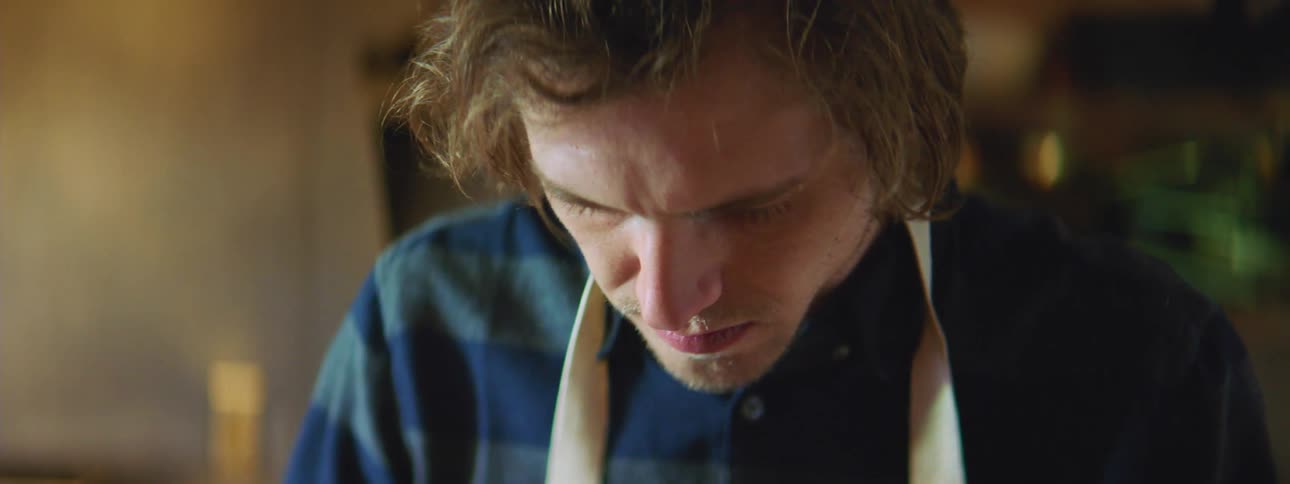 A man wearing an apron looks down as he works