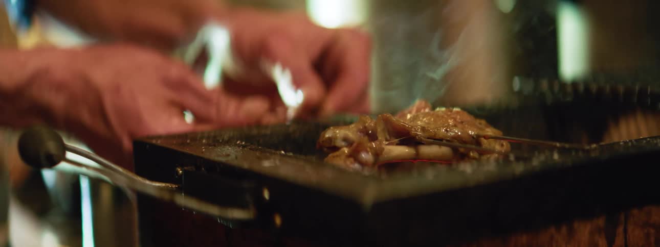 A man turns a skewer over his grill