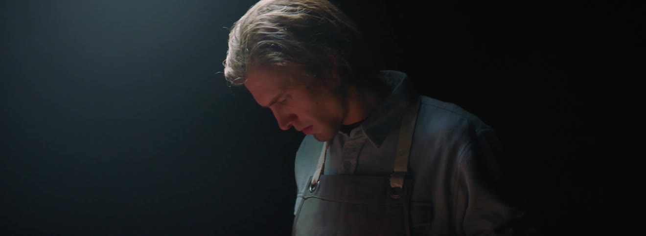 A man is examining a knife in the kitchen