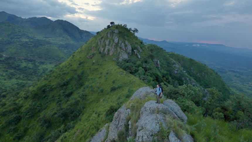 A photographer walking on a large rock formation on the mountains