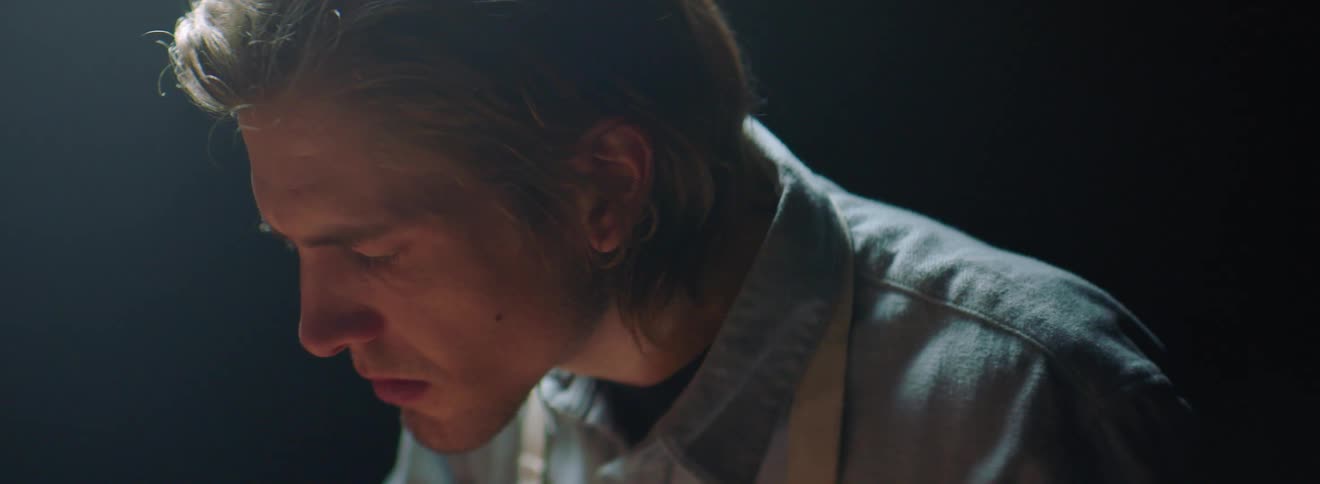 A man is leaning forward in a dark room