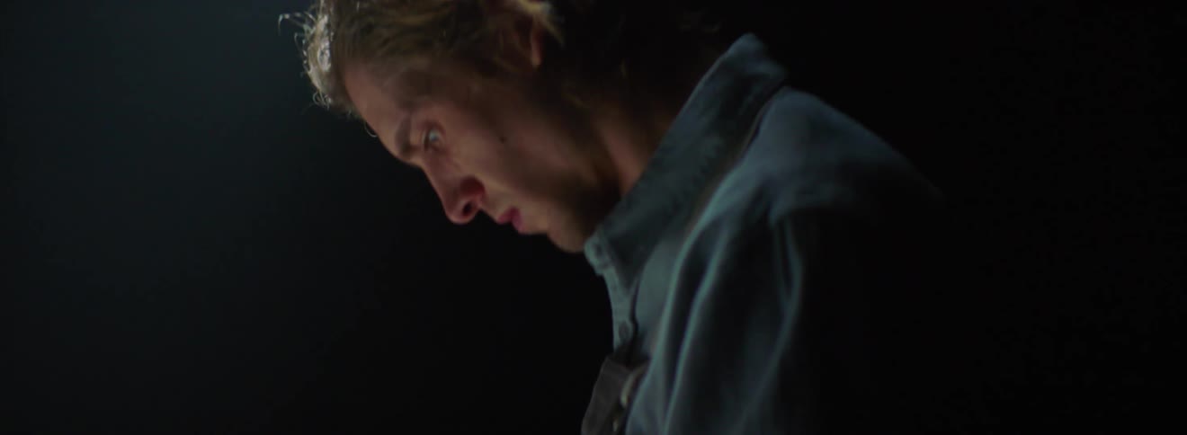 A young white man concentrates on a skinned chicken