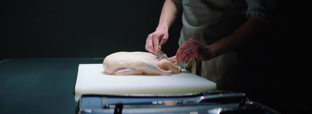 Chef preparing a raw chicken on a cutting board