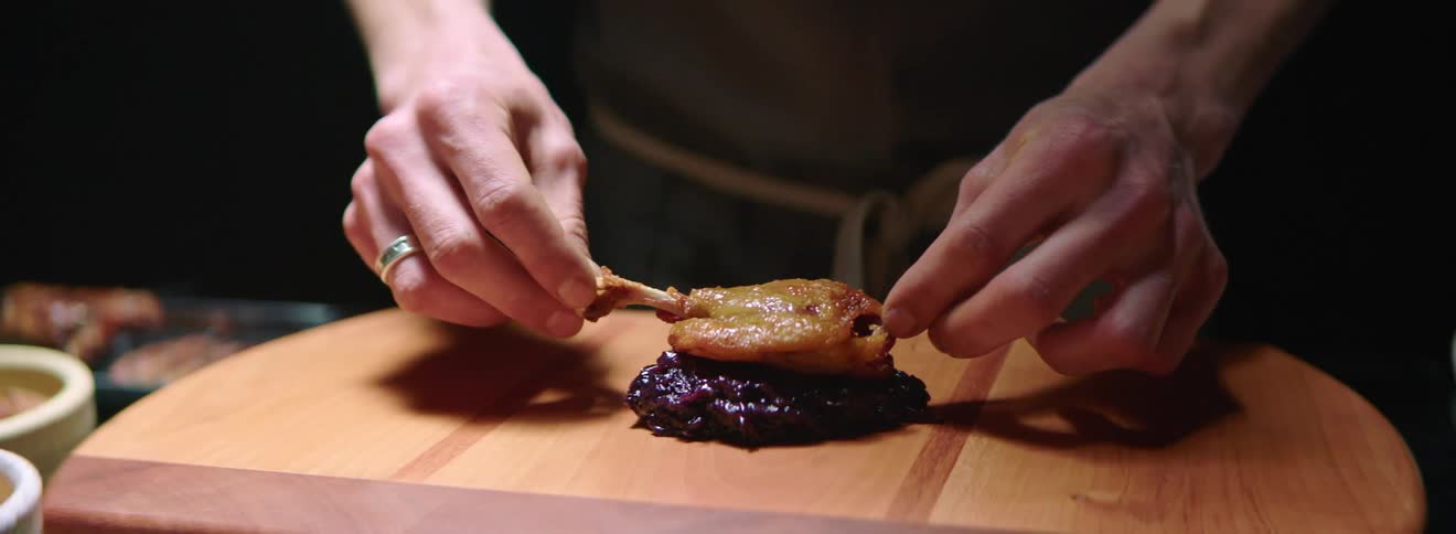 Food being stacked on a wooden cutting board