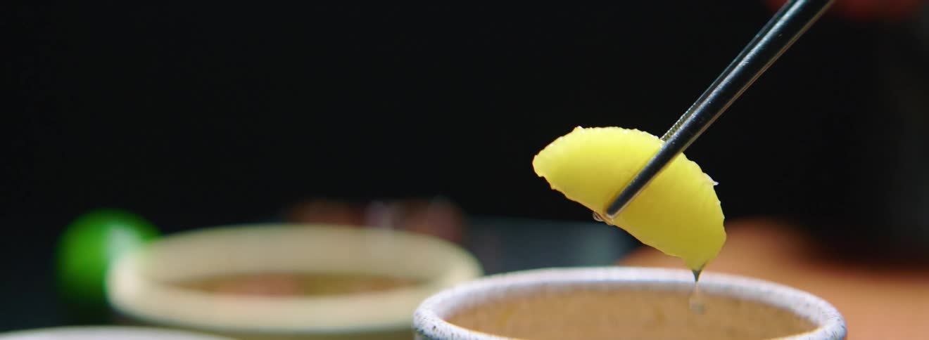 A person uses tweezers to pick an orange segment up out of a container