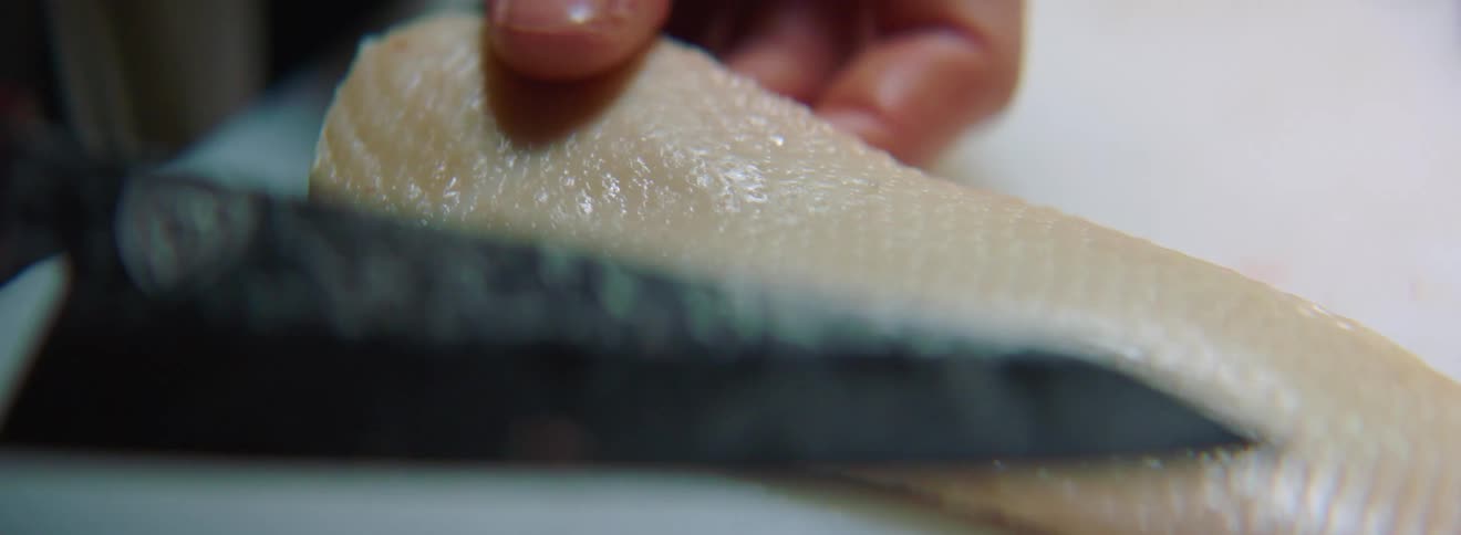 A fillet of meat being flipped on a white table