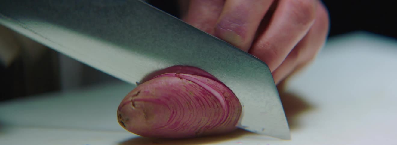 A person cuts a vegetable with a knife