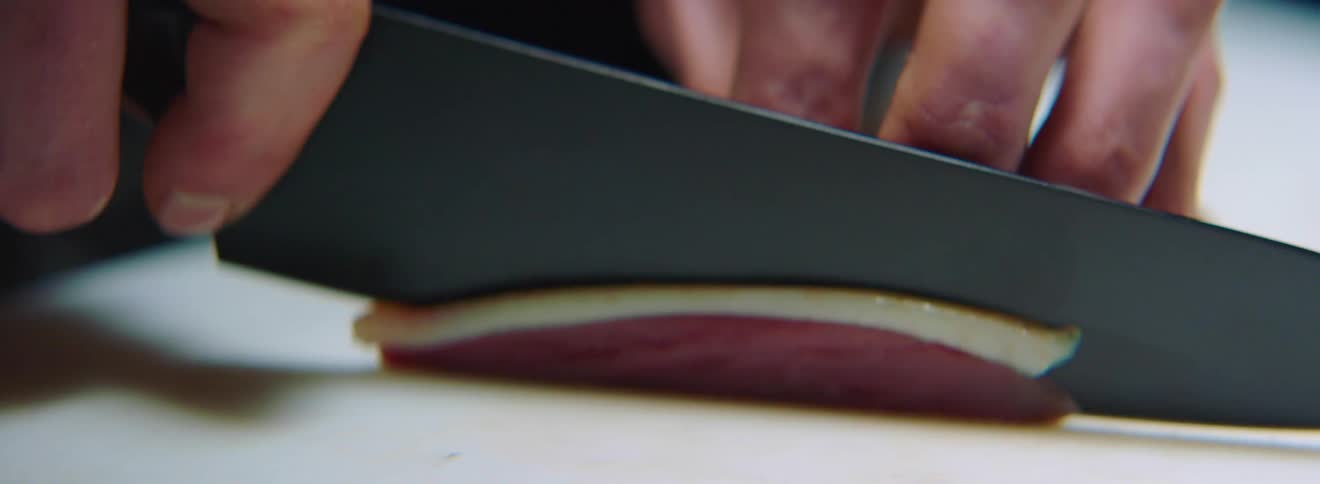 Man slices meat thinly