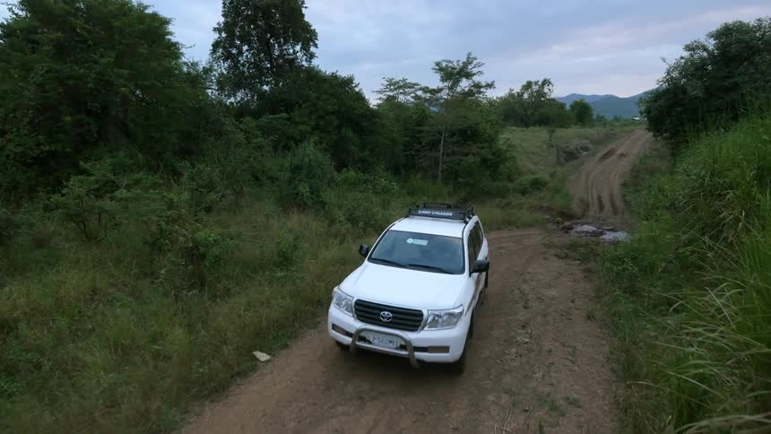 A white vehicle makes its way down a dirt road