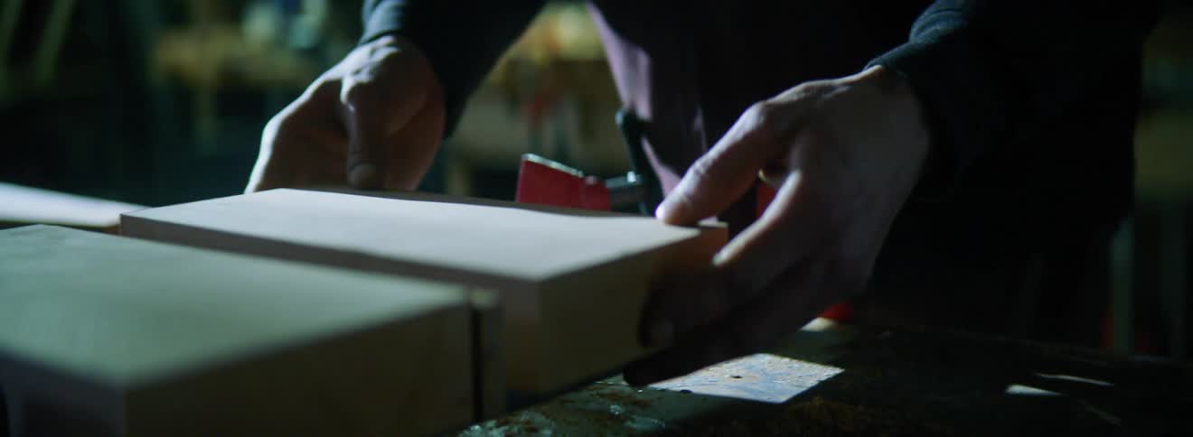 A person arranging blocks of wood on a vice