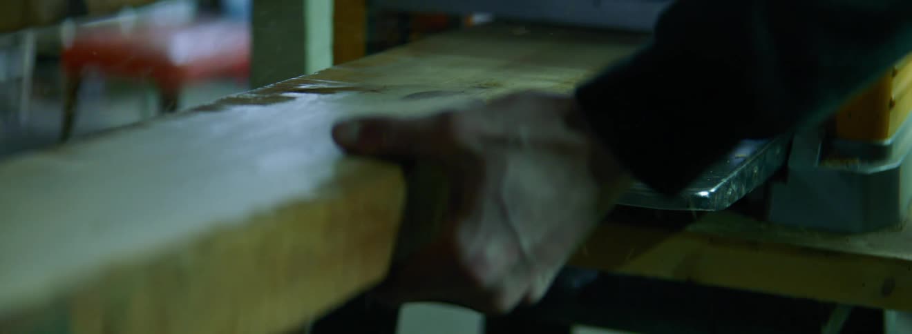 Block of wood is pushed through processing equipment and grasped by person