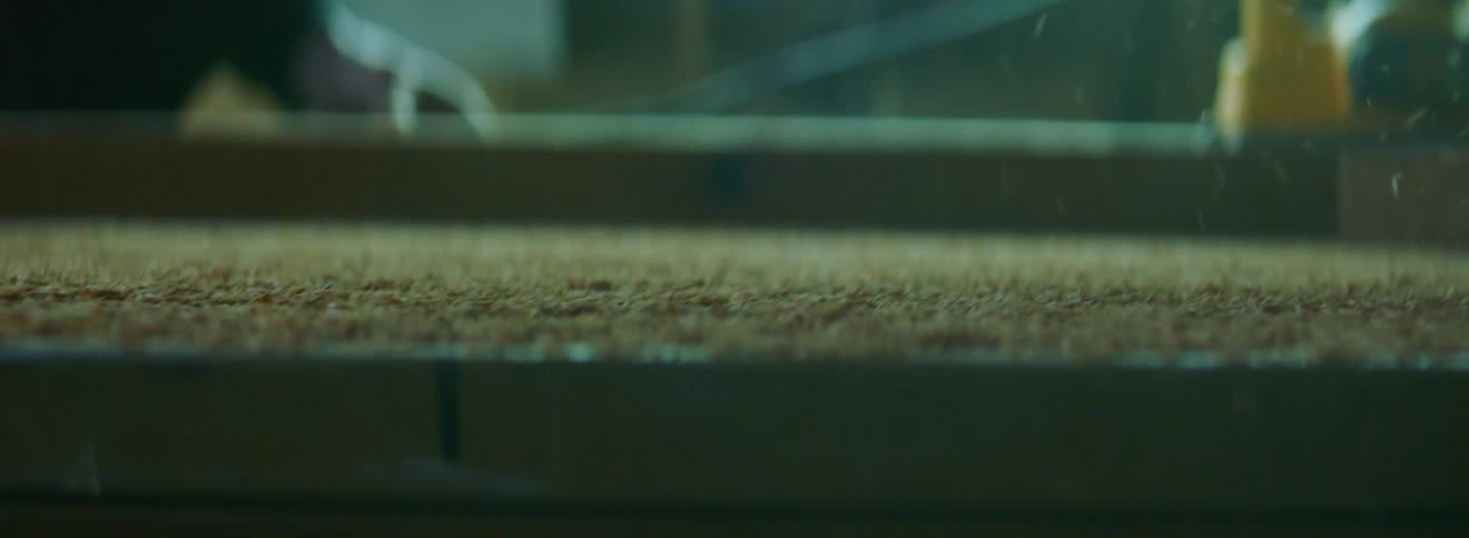 A man uses an electric planer on a piece of lumber in a workshop