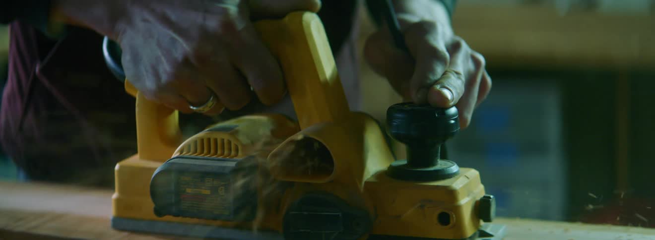 An older person runs a sander across a block of wood