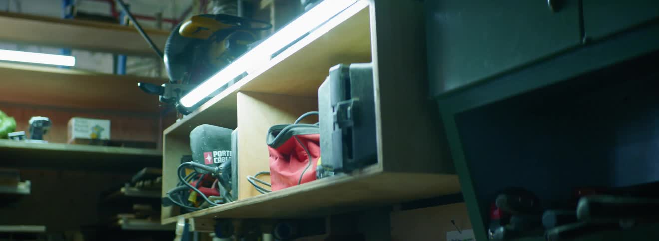 A fluorescent light on a wall mounted wooden shelf lighting up