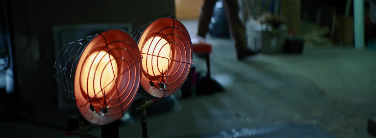 A pair of lights burn inside a room as a man walks by in the background