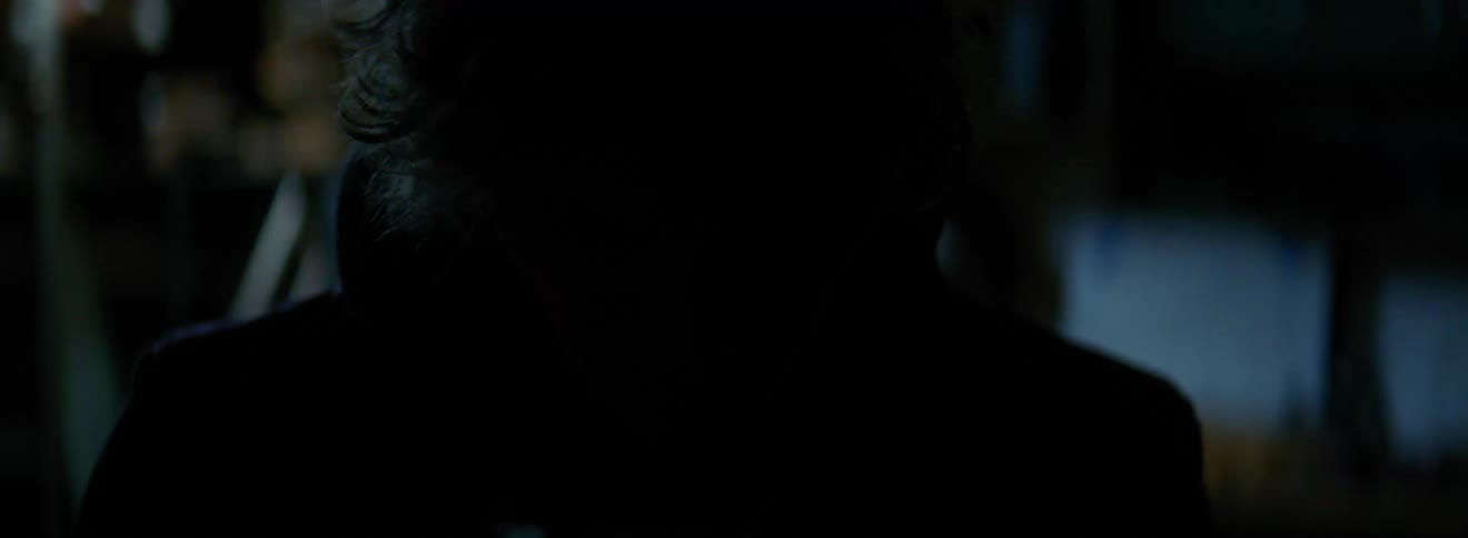 A man stands in a garage looking down while lights are flashing