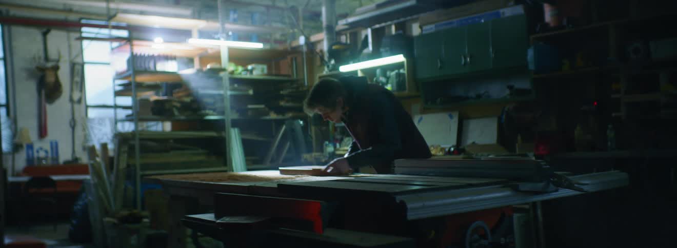 A man examining a wooden board in a workshop