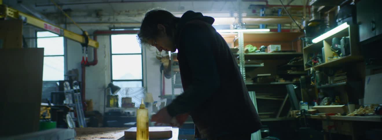 A young man cleans a block of wood in a workshop
