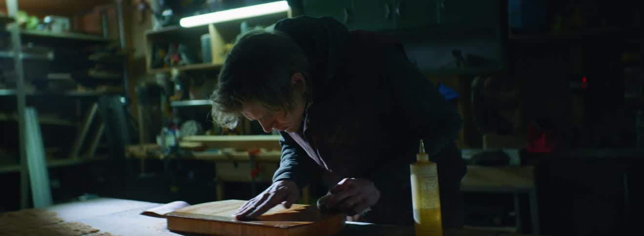 A male caucasian is rubbing oil onto a piece of wood
