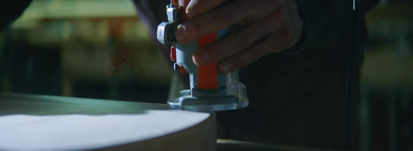 A man uses a machine to cut into wood