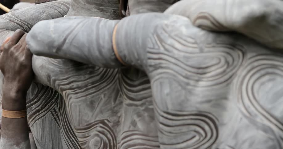 Tribesmen stand arm in arm while wearing their traditional body paint