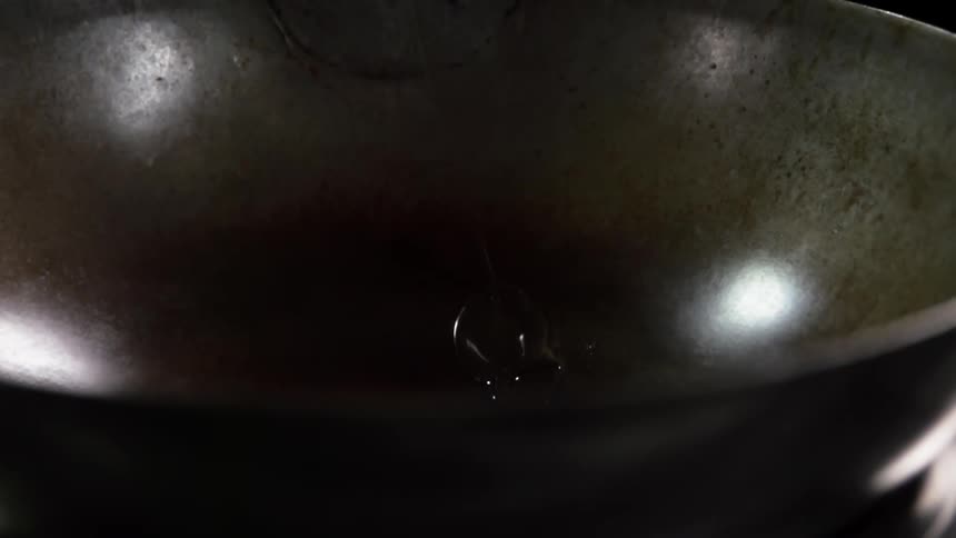 Oil is poured into wok reflecting the light