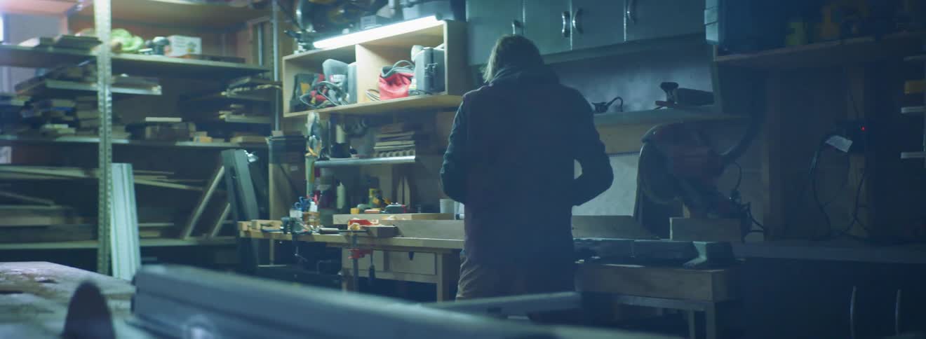 A man uses a hand planer on a board