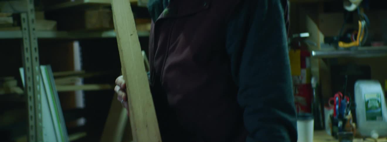 Man looks through planks of wood on a shelf and picks out one