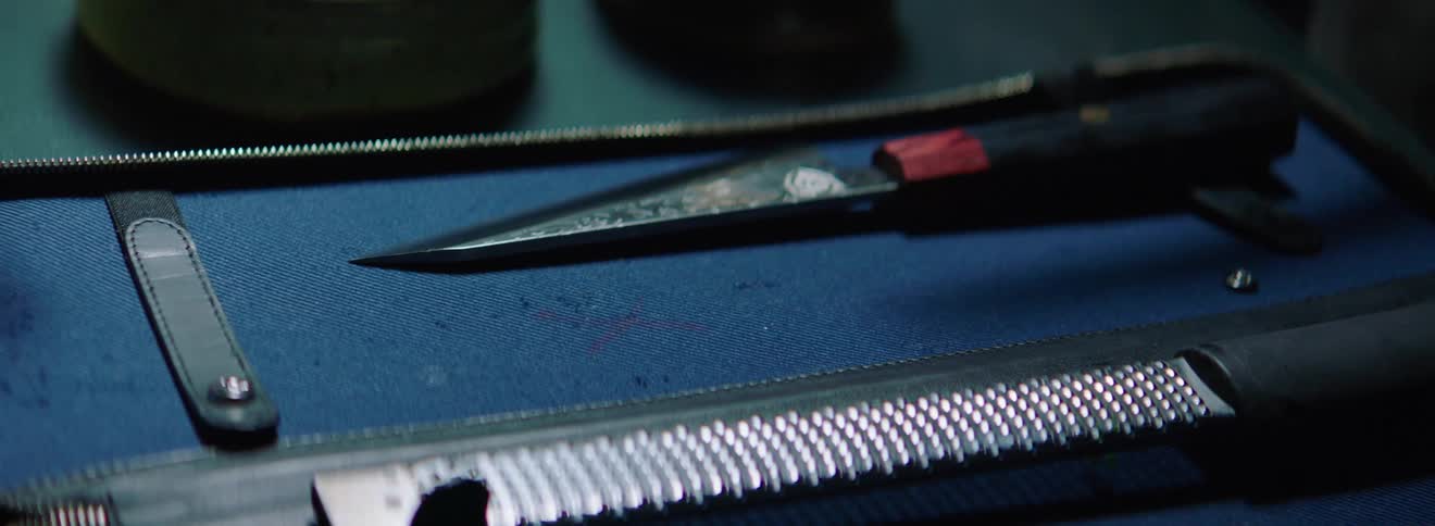 A white man grabs a cooking knife out of a case