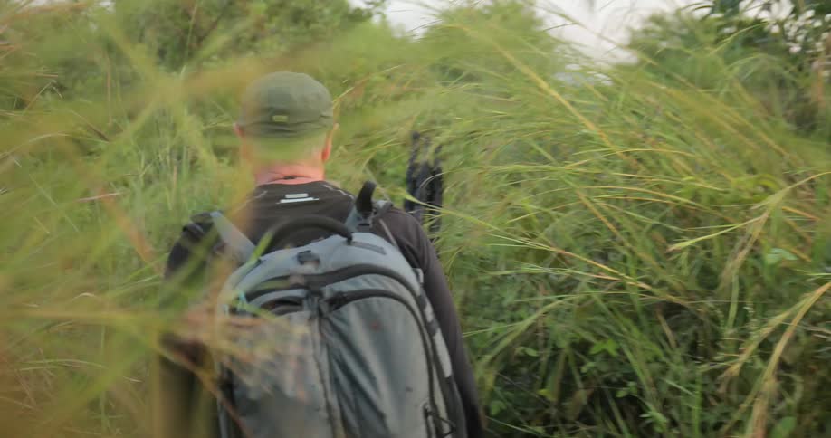 Two men are hiking in a dense wooded area