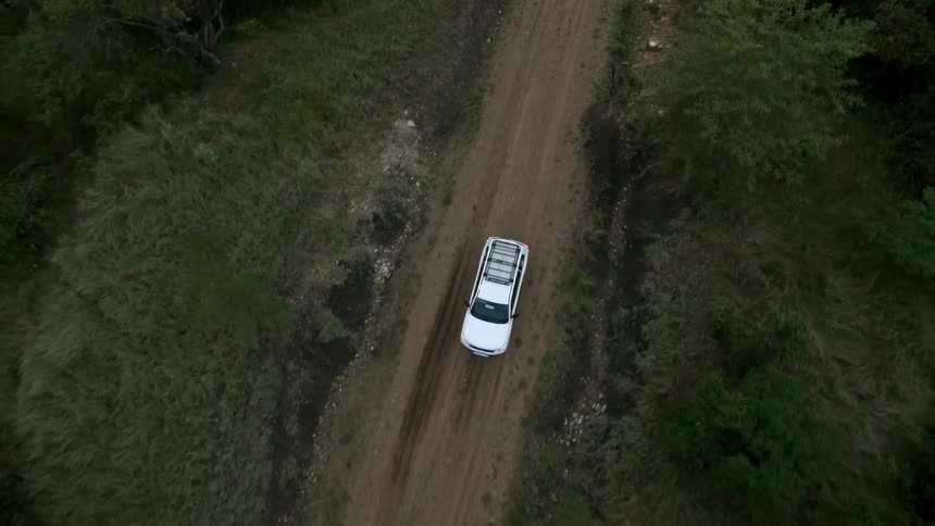 A white vehicle makes its way down a dirt road