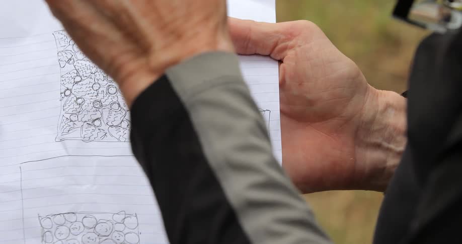 A man using his finger to trace a circle around a sketch